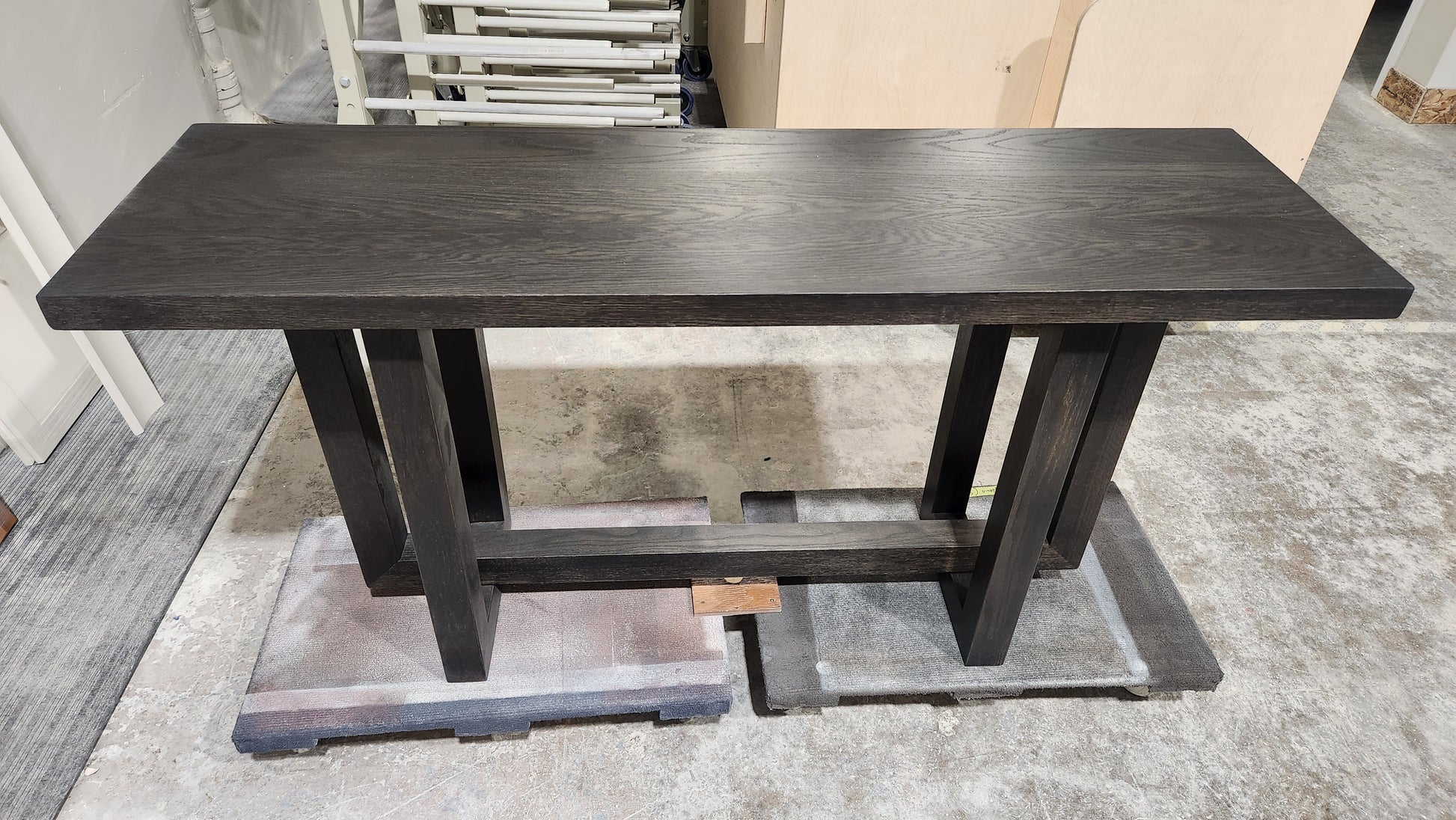 Dark wooden console table on a gray floor with a neutral background