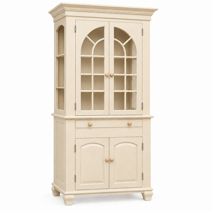 A tall, light natural wood hutch cabinet with two upper glass-front doors featuring arched window panes, a single middle drawer with round silver knobs, and two lower arched cabinet doors, shown on a plain white background.