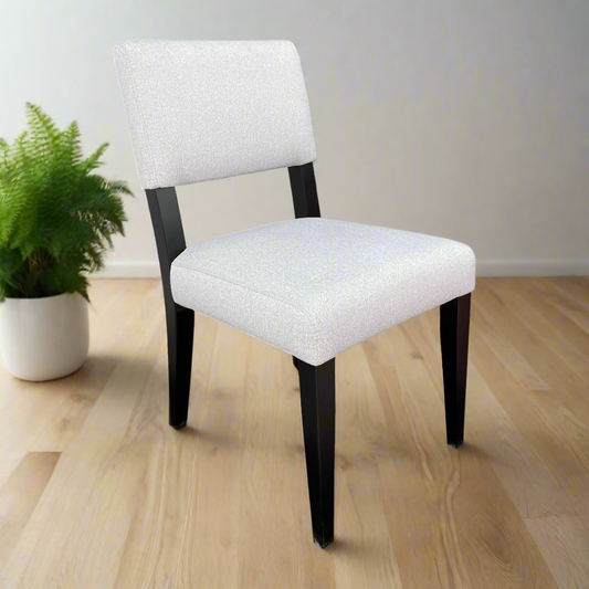 White upholstered chair with black legs on a white background