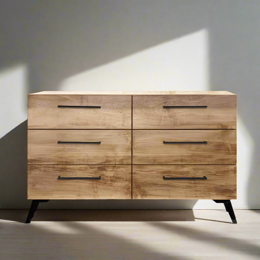 Wooden dresser with four drawers against a neutral wall