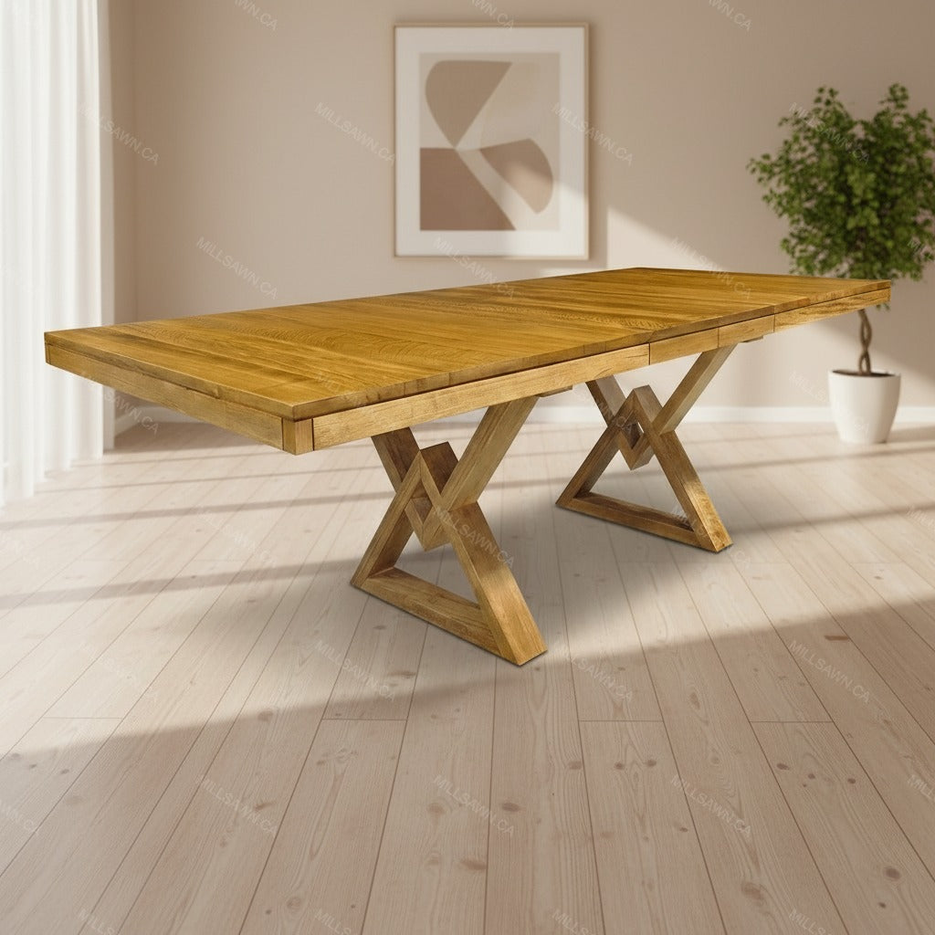 Wooden dining table with X-shaped legs in a room with a plant and abstract art on the wall.